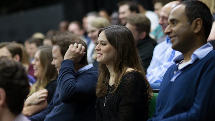 RADA Business course participants watch a presentation in an auditorium.