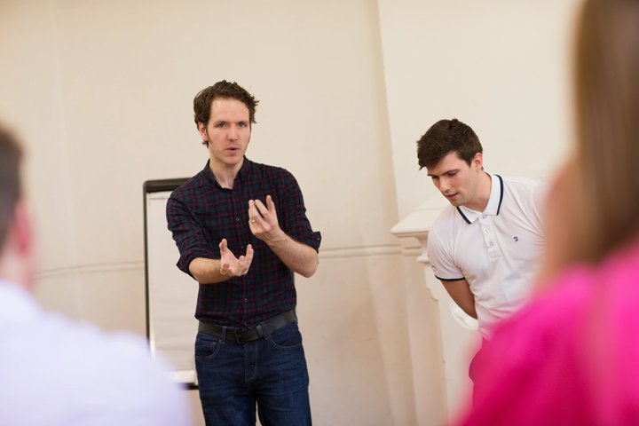 © J Tucker A RADA Business tutor is standing and presenting a speech in a rehearsal studio.