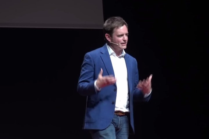 A RADA Business tutor is standing and presenting a TEDx talk.