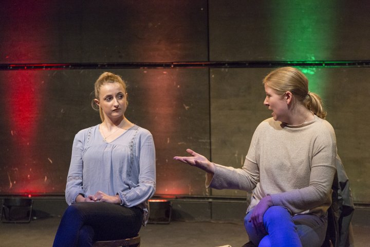 Two RADA graduates perform in a colourfully lit theatre.