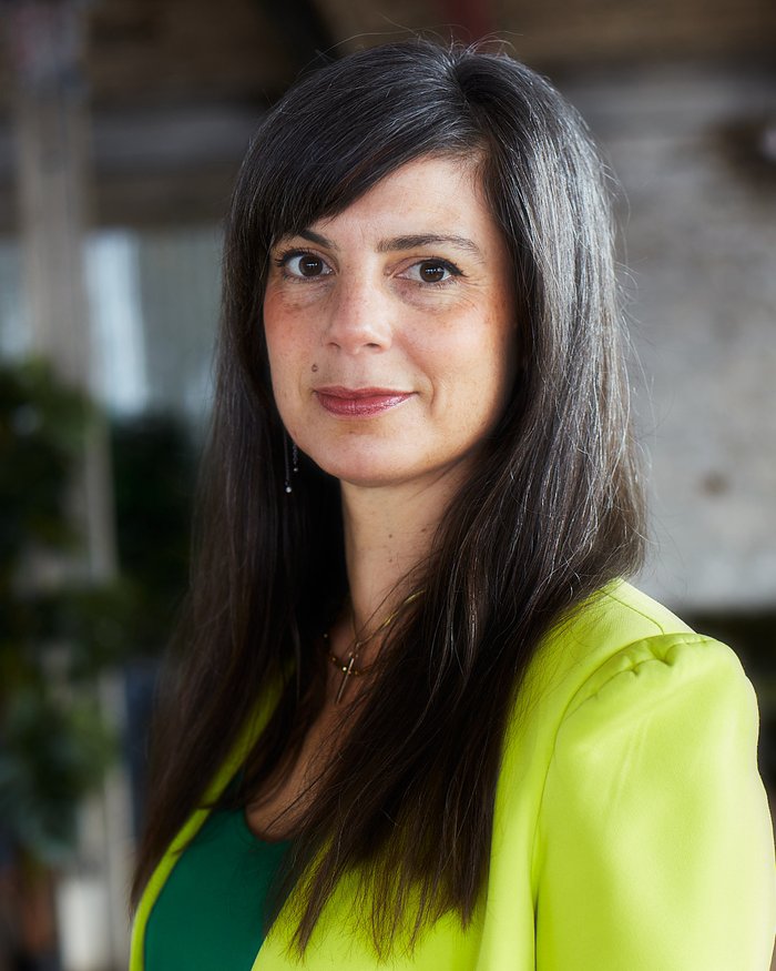 Headshot of RADA Business Practitioner, Imogen Butler-Cole, looking to camera in a green jacket