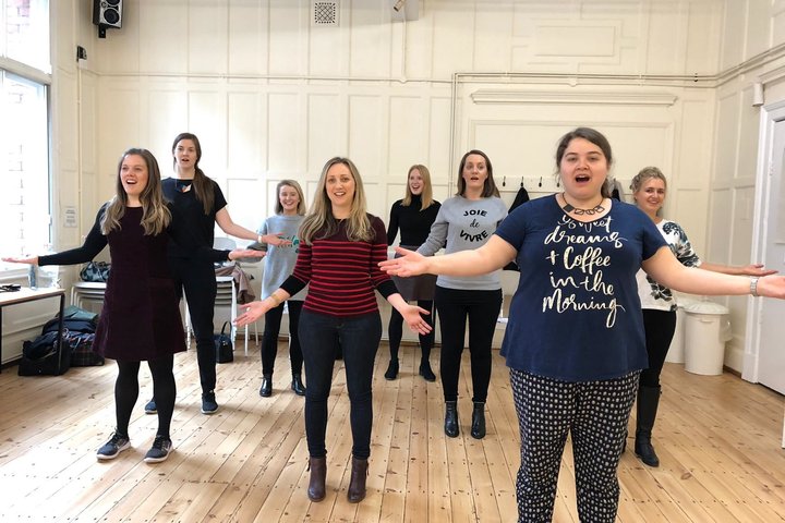 © Rebecca Farmer and her colleagues A group of women stand in a rehearsal room. They are holding their arms out horizontally.