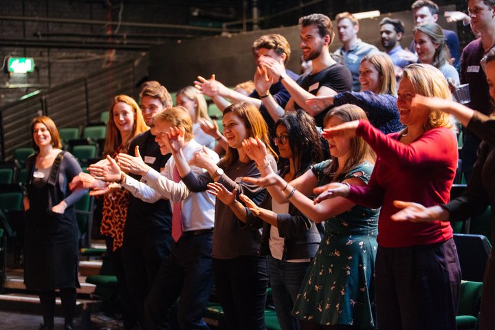 RADA Business participants and tutors applaud a presentation in a theatre.