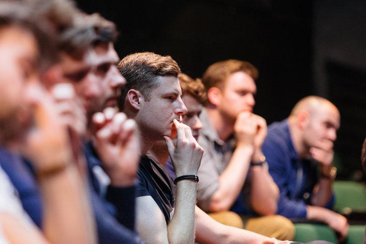 A group of audience members watch a presentation.