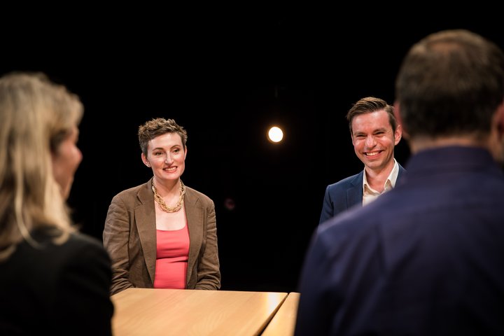 RADA Business participants sit around a table in an empty theatre auditorium. They are laughing.