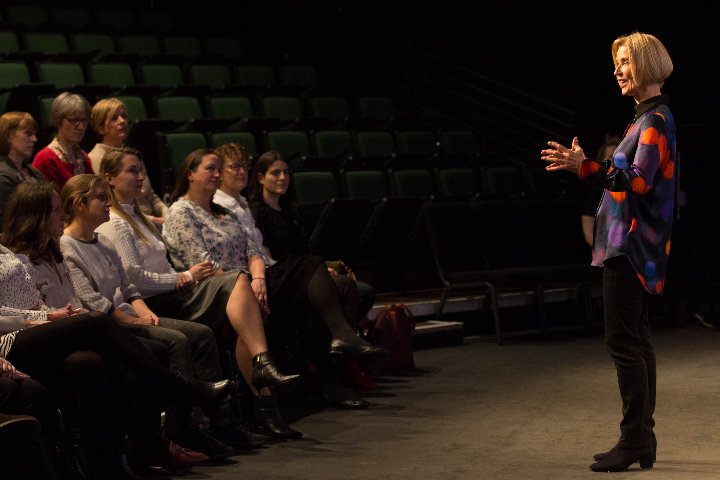 © Briony Campbell 2020 A woman stands in front of a small audience, seated in a theatre