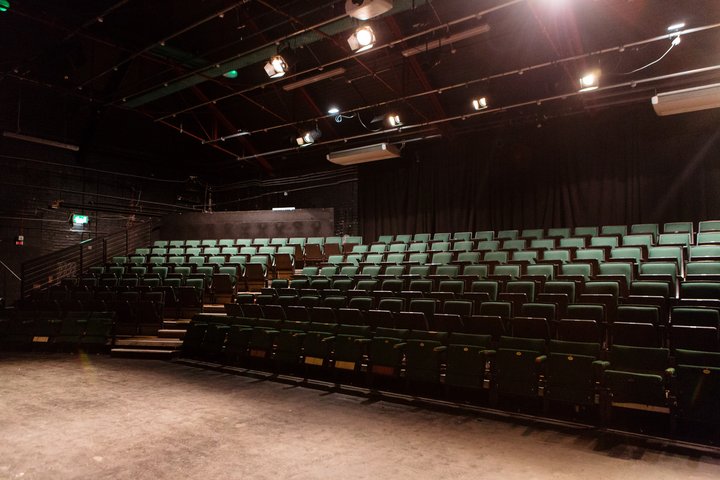 © Helen Murray A large empty theatre with raked, green seating.