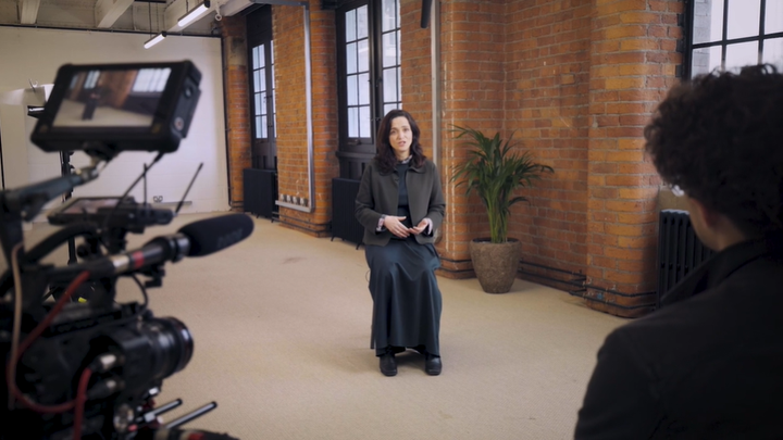 RADA Business tutor, Kate Walker Miles, sits on a chair in a large room with a bay window - she is speaking to camera.