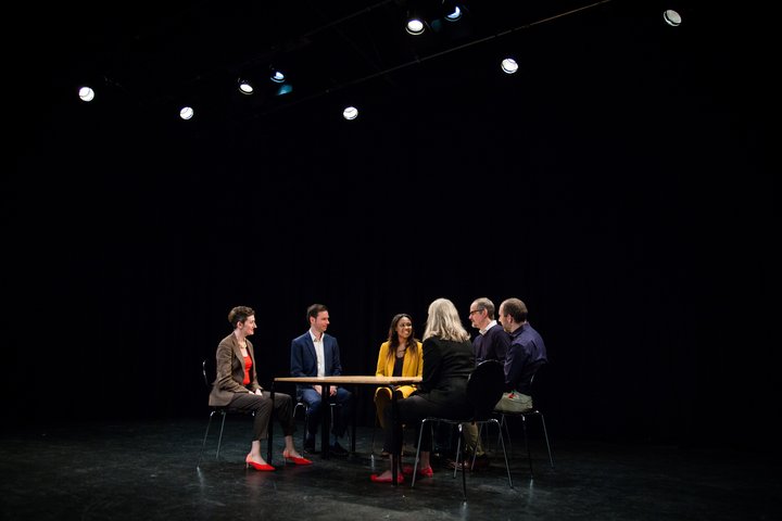 A group of RADA Business participants take part in a meeting in a theatrical space.