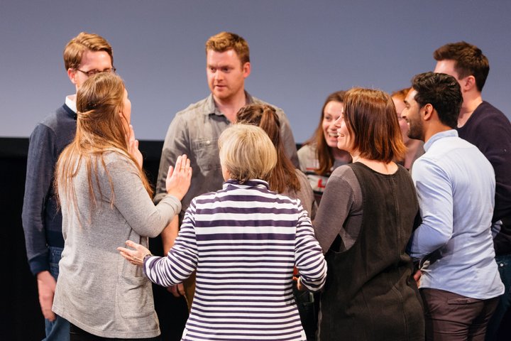 © Helen Murray RADA Business course participants huddle together in a theatre, discussing something.